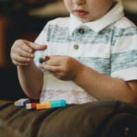 Autism therapy child playing with colored blocks Photo by Caleb Woods on Unsplash