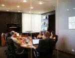 Corporate meeting with individuals around a board room table with laptops Photo by Campaign Creators on Unsplash