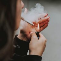 person lighiting a cigarette Photo by lilartsy on Unsplash